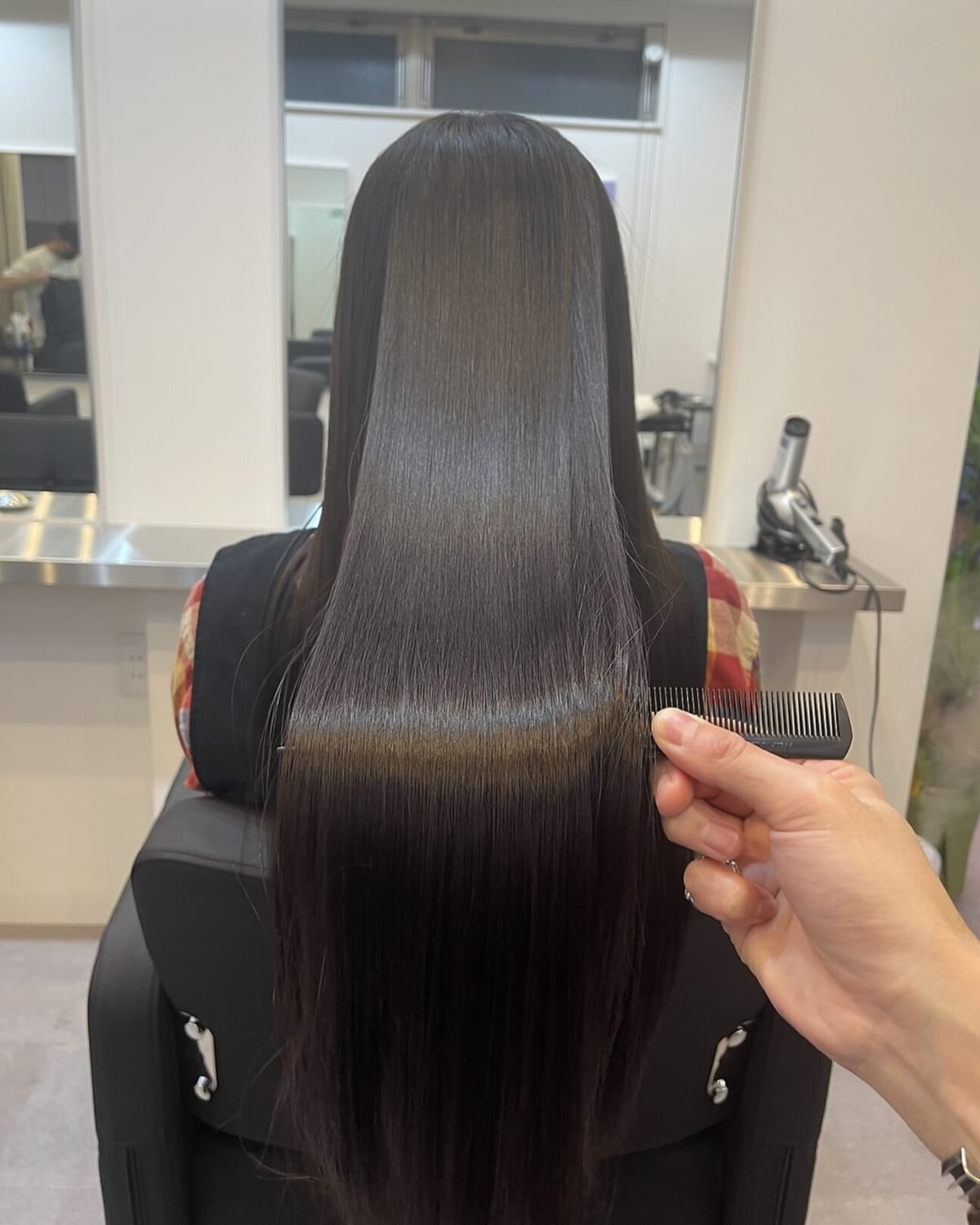 髪質改善ストレートの仕上がり。艶のあるロングヘアにコームを通した状態